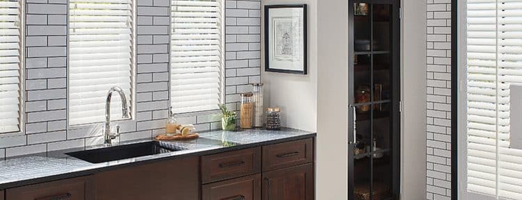 Custom-made window blinds covering three windows above a sink and counter and also covering a uniquely shaped set of doors.